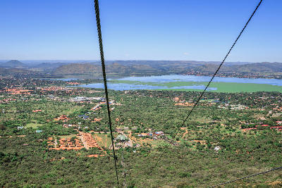 View of Hartbeespoort Dam from the Hartbeespoort Aerial Cableway, with cable lines descending over the Magaliesberg foothills in North West Province, South Africa.