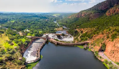 Aerial view of Hartbeespoort Dam spillway and Crocodile River flowing through a rocky Magaliesberg valley in North West Province, South Africa.
