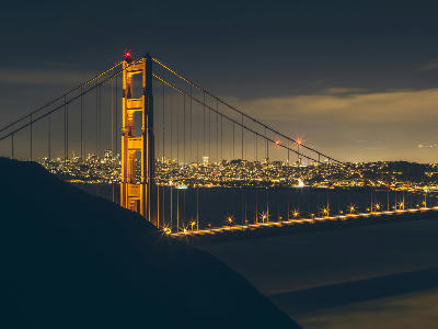 Golden Gate Bridge illuminated at night with San Francisco city lights in the background, viewed from Hawk Hill, California