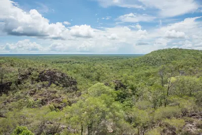 Panoramic view of rocky hills and extensive green tropical woodland beneath a partly cloudy sky in Litchfield National Park, Northern Territory, Australia.