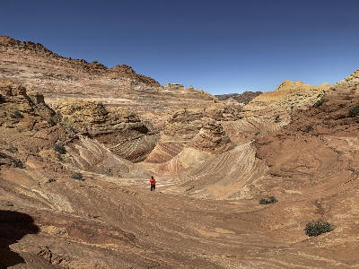 Hiker standing within curved layered sandstone formations at The Wave Coyote Buttes North Arizona