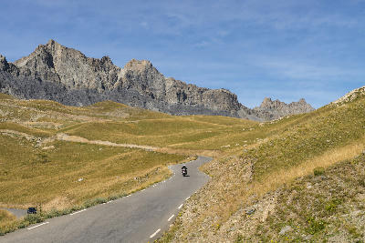 Mountain road winding through dry alpine slopes below rocky peaks in Mercantour National Park