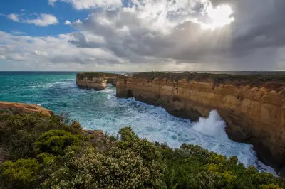 Rugged limestone coastline and London Arch in rough seas at Port Campbell National Park, Victoria.