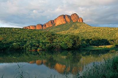 Sandstone mountain cliffs reflected in a calm waterhole at Marakele National Park, surrounded by bushveld vegetation in the Waterberg region of Limpopo, South Africa.