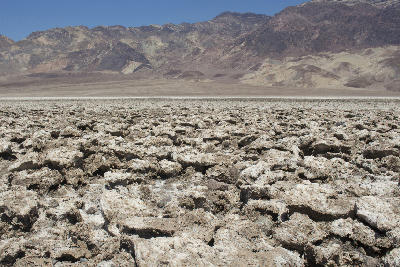 Devil’s Golf Course salt formations in Death Valley National Park with rough jagged salt crust and desert mountains in background