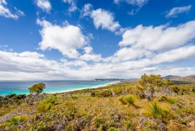 Elevated view across coastal heathland to the long white sands and turquoise waters of Friendly Beaches in Freycinet National Park, Tasmania.