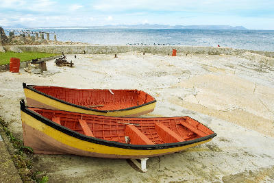 Traditional wooden fishing boats at Hermanus Old Harbour on the rocky Walker Bay coastline in South Africa.