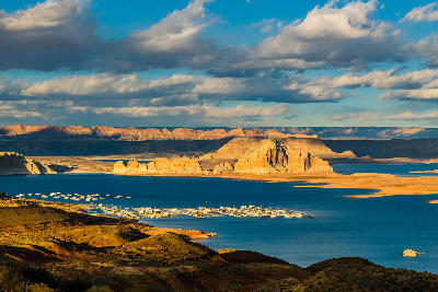 Wahweap Overlook view of Wahweap Marina at Lake Powell in Page, Arizona, showing houseboats on blue water surrounded by layered sandstone cliffs and desert landscape.