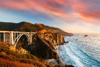 Bixby Creek Bridge on Big Sur coastline with cliffs and Pacific Ocean at sunset in California