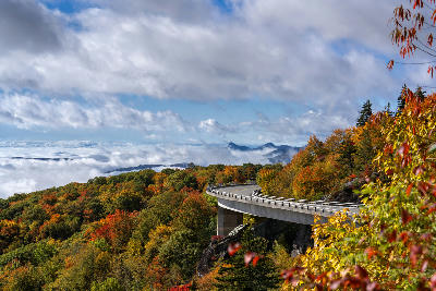 Linn Cove Viaduct curving through autumn forest above low cloud in the Blue Ridge Mountains of North Carolina.