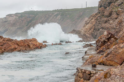 Large waves breaking against the rocky coastline at The Point tidal pool in Mossel Bay, South Africa.