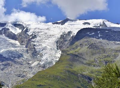 Alpine glacier descending over rocky slopes with exposed ice and surrounding mountain ridges in the French Alps
