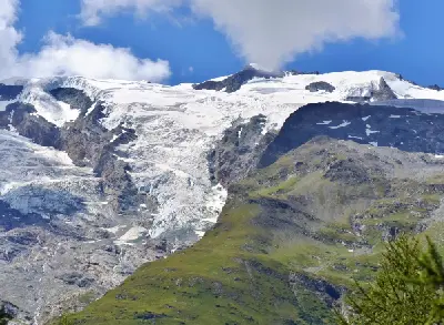 Alpine glacier descending over rocky slopes with exposed ice and surrounding mountain ridges in the French Alps