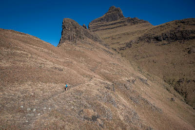 Mountain hiking trail beneath rugged sandstone peaks in the Champagne Castle area of the Central Drakensberg, South Africa.