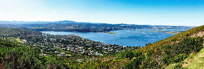 Panoramic view of Knysna Lagoon surrounded by forested hills and coastal landscapes, showing the expansive estuary system of the Garden Route in South Africa.