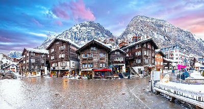 Central square in Zermatt village with traditional wooden chalets and surrounding alpine slopes in winter, Switzerland.