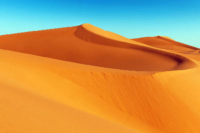 Golden sand dune ridges at sunrise in Erg Chebbi Desert near Merzouga, Morocco.