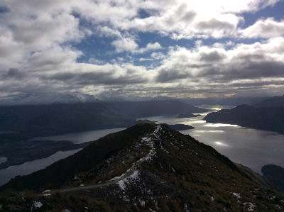 Ridge trail leading to Roys Peak summit with panoramic views of Lake Wanaka and surrounding mountains in New Zealand.