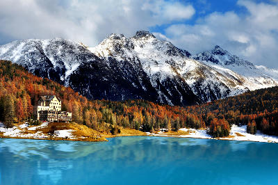 Lake St. Moritz with turquoise water, autumn forest, and snow-covered peaks in Engadin, Switzerland.
