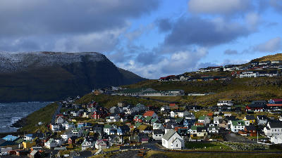 Eiði village with white church and colorful houses on a coastal hillside in Streymoy, Faroe Islands.