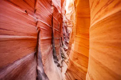 Narrow passage through Zebra Slot Canyon with sweeping red, orange and cream bands across sculpted sandstone walls.