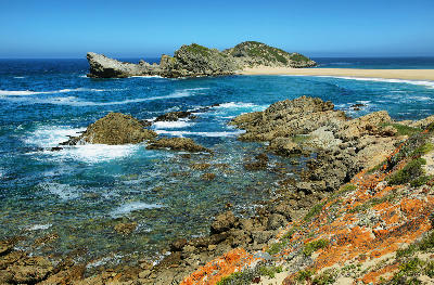 View of Robberg Peninsula with rocky headlands, clear ocean waters and the famous sand spit near Plettenberg Bay, South Africa.