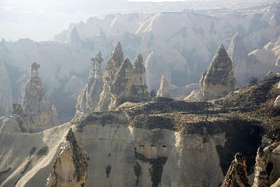 The iconic triple-capped fairy chimney formations rising above the volcanic landscape of Paşabağ (Monks Valley) in Cappadocia, Turkey, with cave dwellings carved into the soft tuff rock.