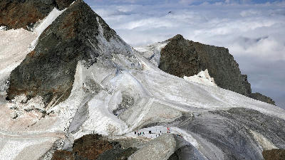 Snow-covered ridge on Jungfraujoch with visitors standing above the glacier in the Bernese Alps, Switzerland.