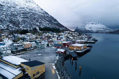 Aerial view of Gryllefjord village with harbour and snow-covered mountains on Senja island, Norway