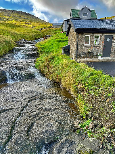 Small stream flowing between houses in Sørvágur on Vágar Island, Faroe Islands.