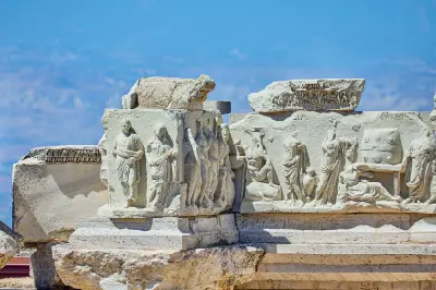 Close-up of carved Roman stone reliefs depicting figures and decorative motifs among the ancient ruins of Hierapolis in Turkey.