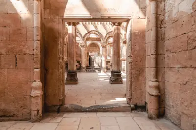 Interior passage framed by carved stone arches and columns inside İshak Pasha Palace in Doğubayazıt, Turkey.