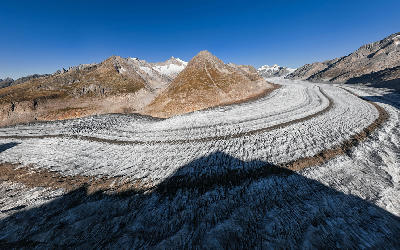 Great Aletsch Glacier sweeping through the valley below Eggishorn, with curved ice bands and surrounding alpine peaks.
