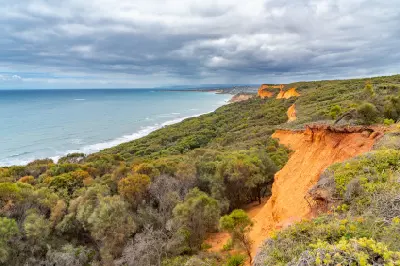 Rugged orange cliffs and dense coastal heath overlooking the ocean at Bells Beach on Victoria’s Great Ocean Road.