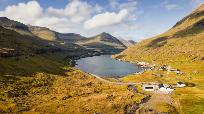 Drone view over Funningsfjørður fjord and small village between steep green hills on Eysturoy, Faroe Islands.