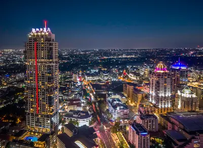 Night view of the Sandton skyline in Johannesburg with The Leonardo tower, Nelson Mandela Square and illuminated office buildings surrounded by city lights.