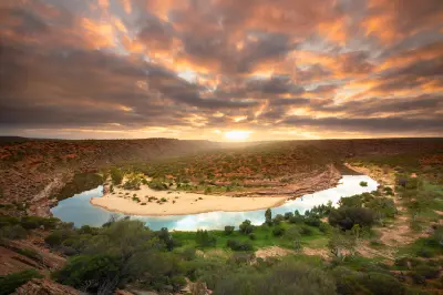 Murchison River curves through the sandstone gorge beneath a dramatic sunrise sky.