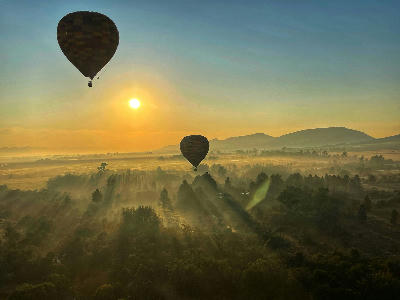 Hot-air balloons floating above the misty Magaliesberg valley at sunrise near Hartbeespoort, South Africa.
