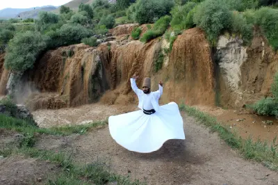 Whirling dervish in traditional white clothing performing in front of Muradiye Waterfall near Van, Turkey.