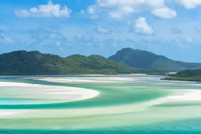 White silica sandbanks and turquoise tidal channels at Hill Inlet with forested hills in the background, Whitsunday Island, Queensland.