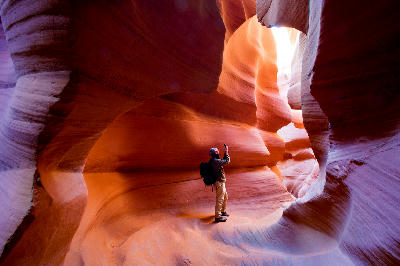Visitor walking through curved sandstone passage inside Antelope Canyon, Arizona
