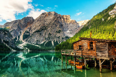 Boathouse on Lago di Braies, set against forested slopes and Dolomite mountain peaks in Italy.