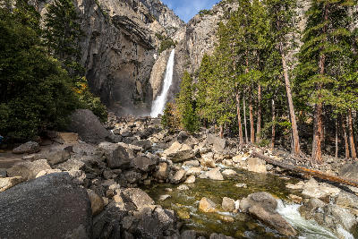 Lower Yosemite Falls cascading over granite rocks beneath steep cliffs in Yosemite Valley, Yosemite National Park, California.