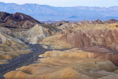 Hiker at start of Golden Canyon loop from Zabriskie Point Death Valley with layered badlands and desert landscape at sunrise