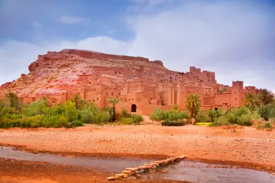 Aït Benhaddou in Morocco showing the earthen kasbah village beside the Ounila River and oasis landscape.