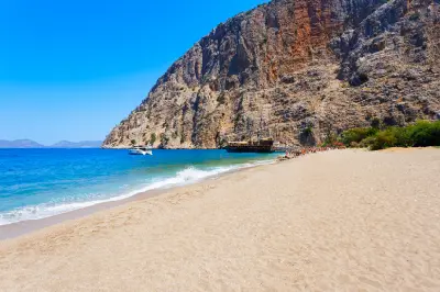 Butterfly Valley Beach with turquoise Mediterranean water, tour boats and towering cliffs near Ölüdeniz, Türkiye.