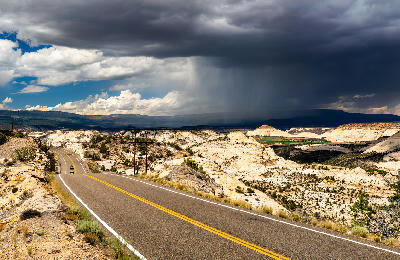 Storm clouds with rain shafts over slickrock desert as Utah State Route 12 crosses the Hogback in Grand Staircase-Escalante National Monument, USA.