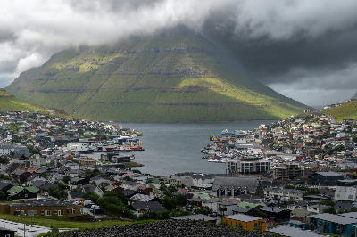 View over Klaksvík harbor and surrounding fjord with layered green mountains on Borðoy in the Northern Islands of the Faroe Islands.
