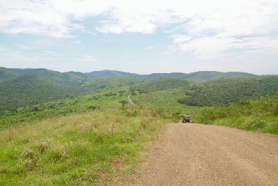 Dirt safari road crossing green hills in Hluhluwe–iMfolozi Park, South Africa.