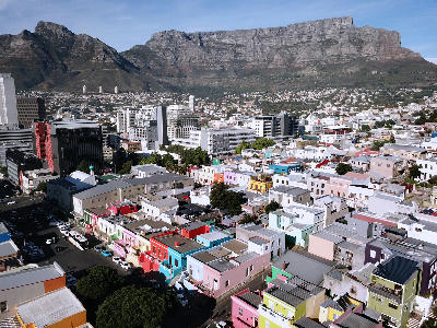 Bo-Kaap neighborhood with brightly colored houses in the foreground and Table Mountain rising above Cape Town in the background.